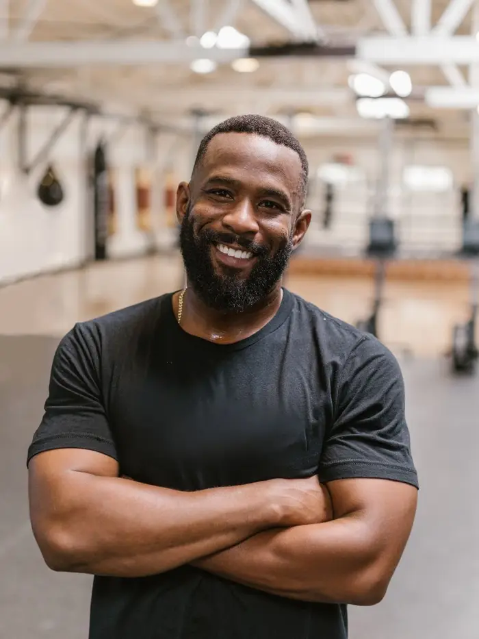 Coach Marcus Hale, smiling with arms crossed on the gym floor