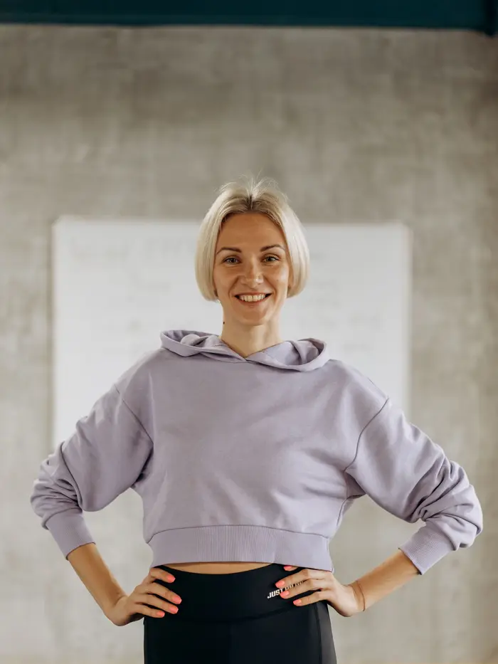 Coach Maya Lindqvist, smiling, hands on hips in front of the gym whiteboard