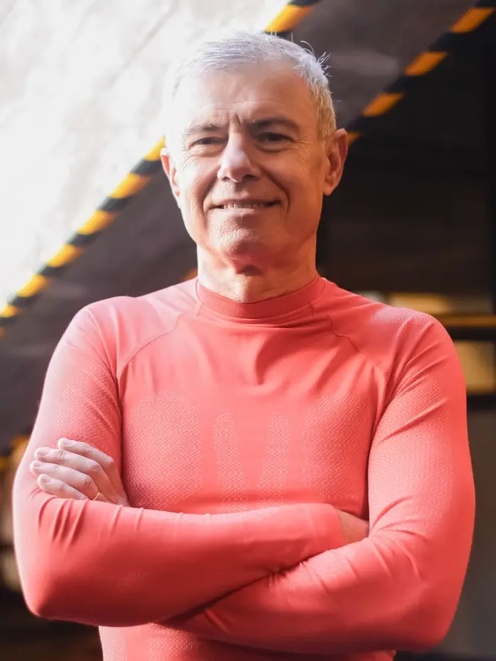 Coach Ray Donnelly, grey-haired and smiling, arms crossed in front of a squat rack